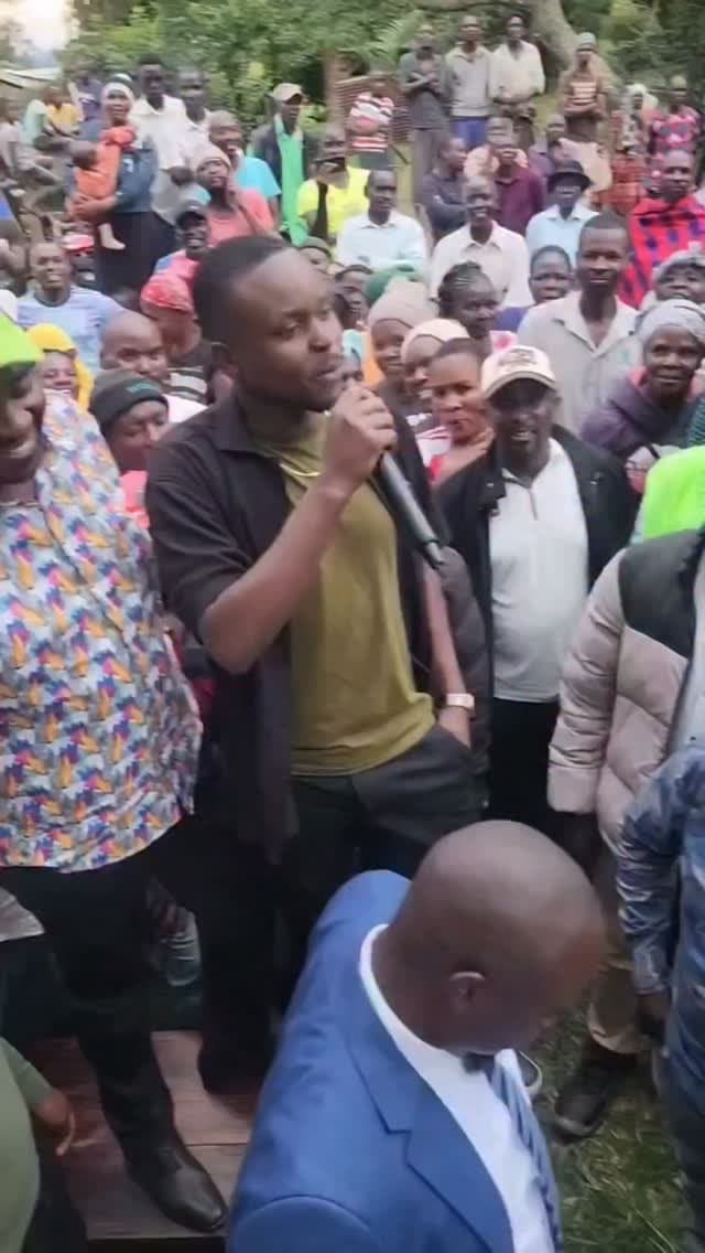 Leon speaking into a microphone surrounded by residents